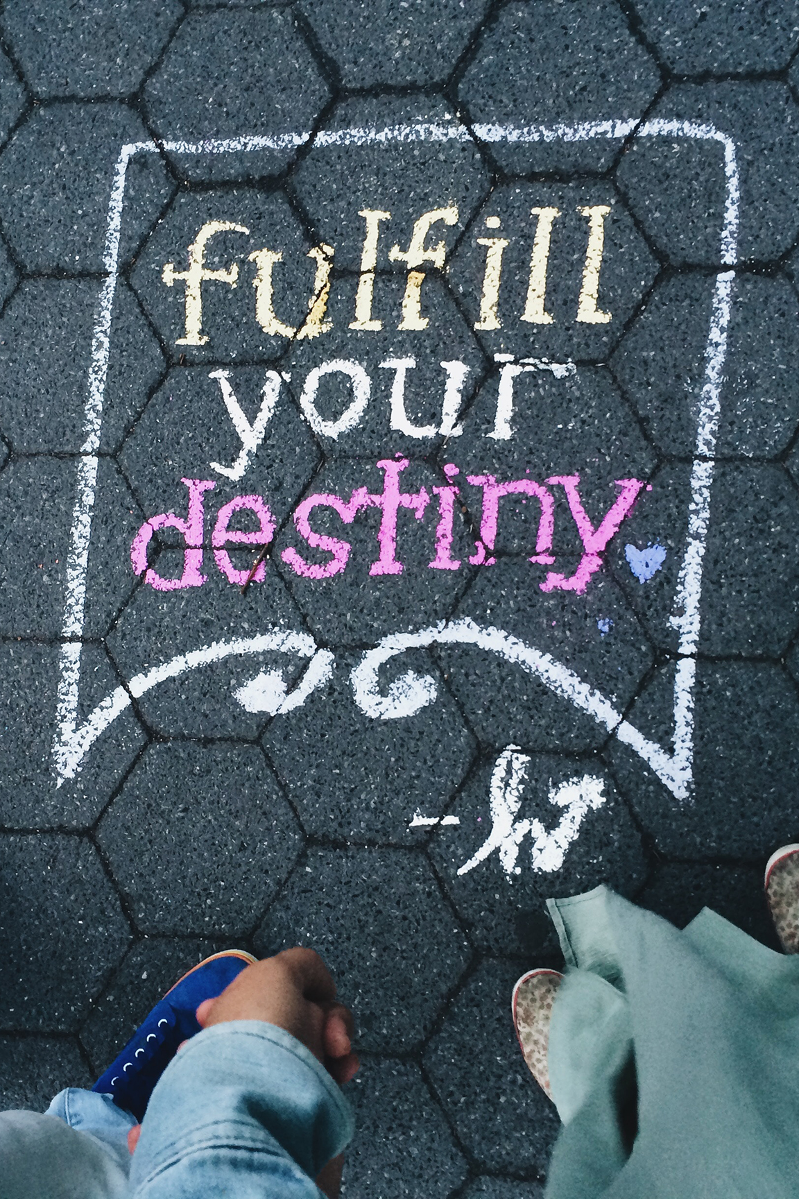 Fulfill your destiny written on the floor with two pair of feet next to it